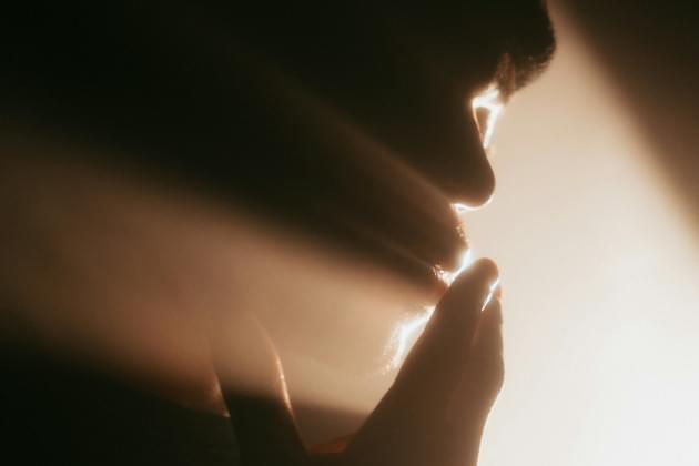Light rays emenating toward a human face with hands reaching toward face.